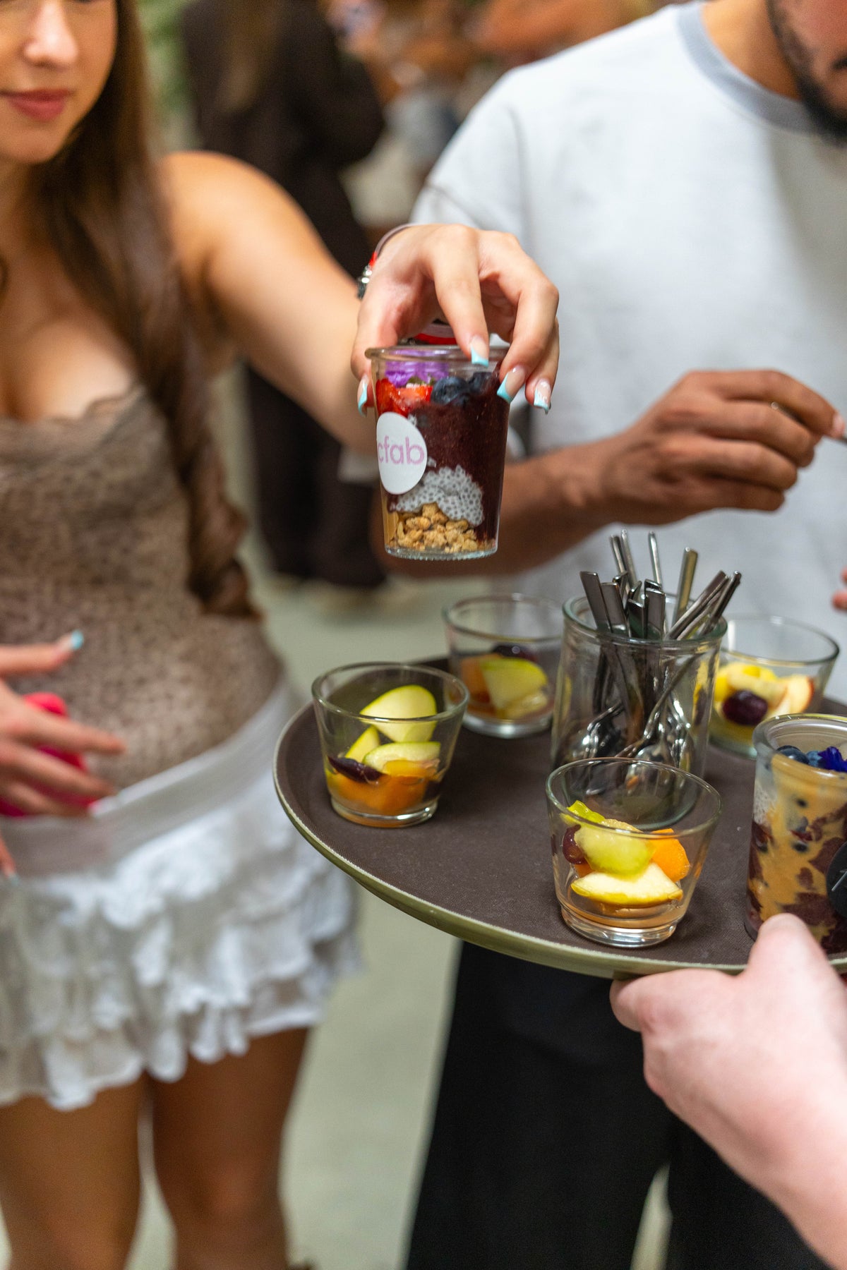 Ein Gast nimmt Açaí im Glas beim Flying Service von KAPLAN&ME entgegen